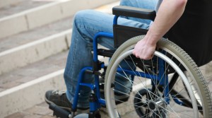 Ein Rollstuhlfahrer steht mit seinem Rollstuhl vor einer Treppe