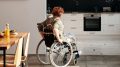 Eine Frau im Rollstuhl fährt vom Esstisch in die Küche.