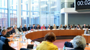 Das Bild zeigt den Petitionsausschuss: Man sieht viele Bundestagsabgeordnete an einem großen runden Tisch sitzen.