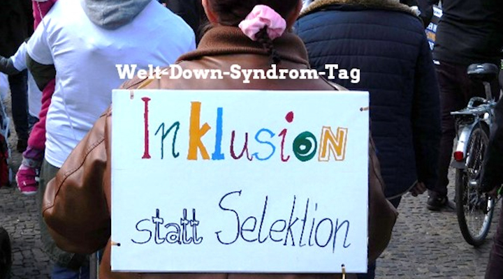 Eine Demonstrantin hat ein Schild auf dem Rücken, auf dem steht: "Inklusion statt Selektion" - Darüber steht der Schriftzug: Welt-Down-Syndrom-Tag