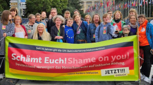 Auf dem Foto sieht man eine Gruppe von Jugendlichen und ihren Eltern, die bei der Staatenprüfung in Genf am 29./30.8.2023 für inklusive Bildung demonstriert haben. Meine Kollegin Stephanie Aeffner (MdB), Katrin Langensiepen (MdEP) und ich sind auch dabei. Wir alle stehen hinter einem Transparent, auf dem steht: Seit 14 Jahren gilt die UN-Behindertenrechtskonvention – Schämt Euch! Shame on you! – Deutschland verweigert das Menschenrecht auf inklusive Bildung.